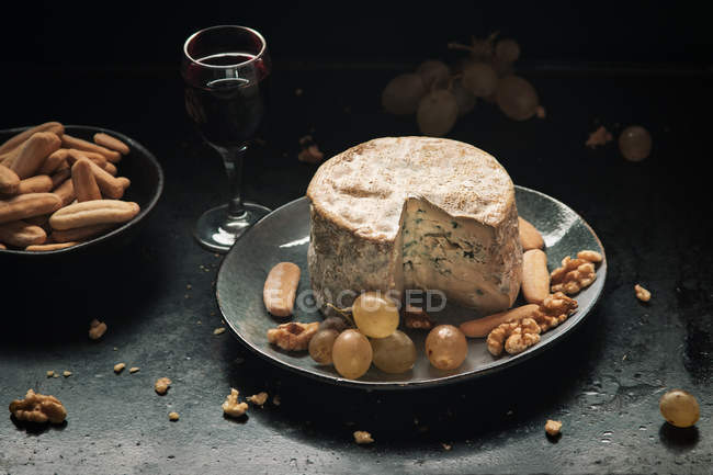 Натюрморт синього сиру з виноградом і волоськими горіхами на темній поверхні — стокове фото