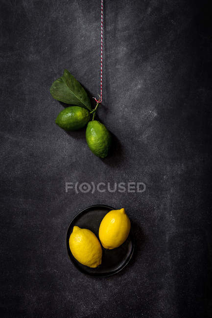 Nature morte de citrons frais et de citrons verts sur la table noire . — Photo de stock
