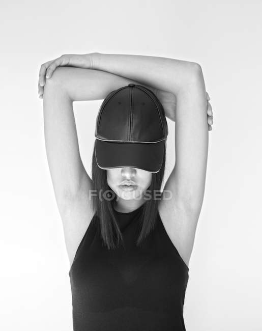 Mulher muito elegante em cap posando com braços cruzados levantados em estúdio — Fotografia de Stock