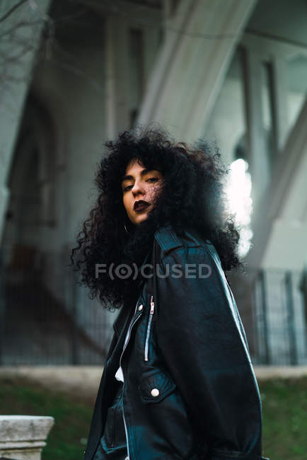 Curly woman posing in city and looking at camera — Stock Photo