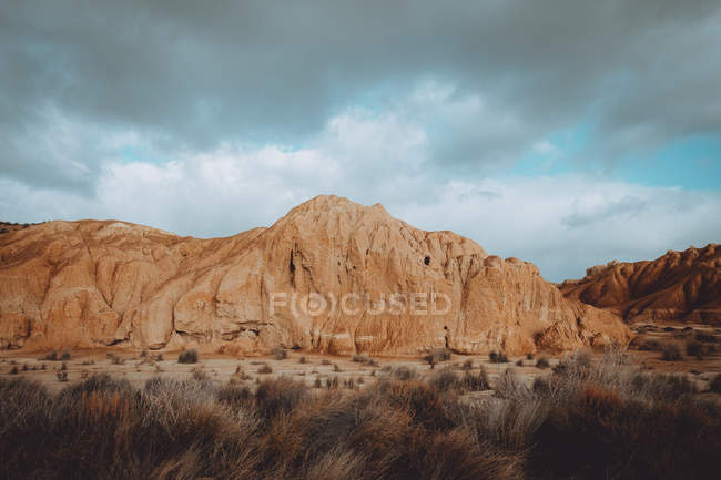 Вид на сухие песчаные скалы и траву в облачный день . — стоковое фото