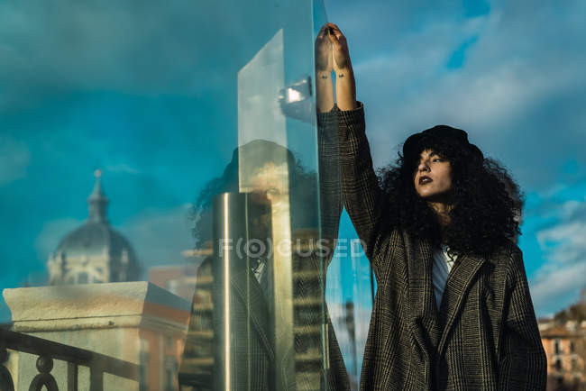 Attractive woman at glass case reflecting city buildings — Stock Photo