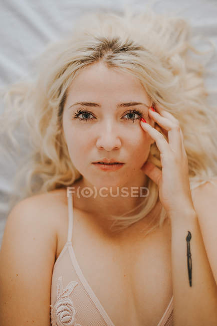 Porträt einer sinnlichen blonden Frau, die auf dem Bett liegt — Stockfoto
