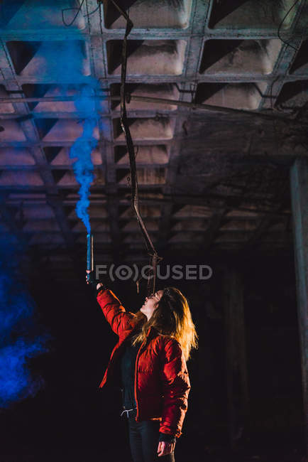 Femme posant avec la torche bleue fumant dans la main tendue — Photo de stock