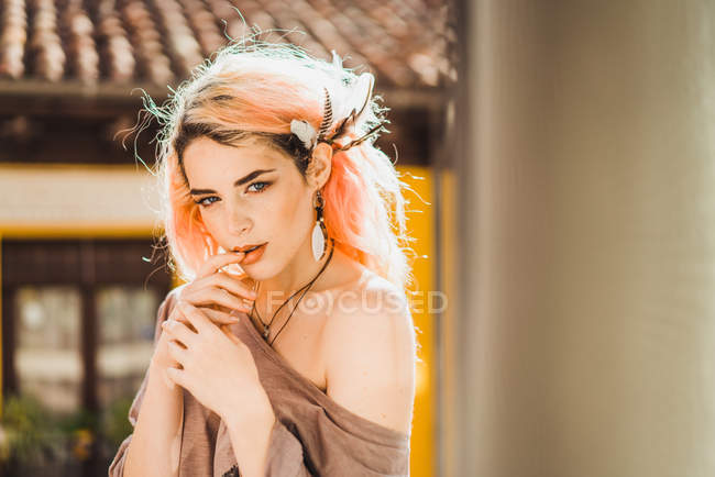 Sensual mujer con el pelo rosa posando en el balcón y mirando a la cámara - foto de stock
