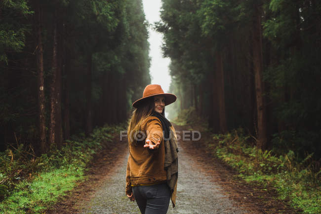 Mujer haciendo sígueme gesto en camino rural en bosques - foto de stock