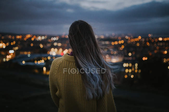Вид ззаду жінка захоплюється освітленим міським пейзажем — стокове фото