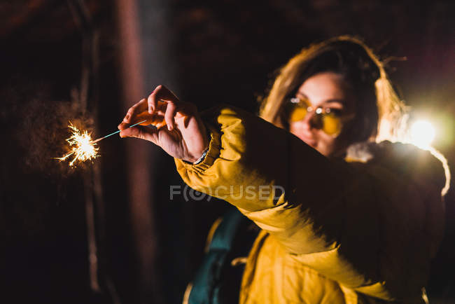 Woman holding lighting sparkler in outstretched arm — Stock Photo