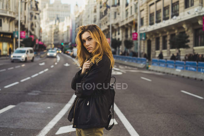 Vista laterale della donna bionda in posa su strada e guardando la fotocamera — Foto stock