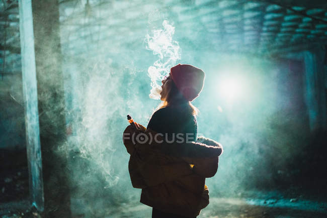 Side view of young woman vaping in abandoned building — Stock Photo