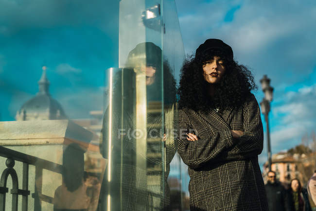 Attraktive Frau lehnt an Glas und blickt in die Kamera — Stockfoto
