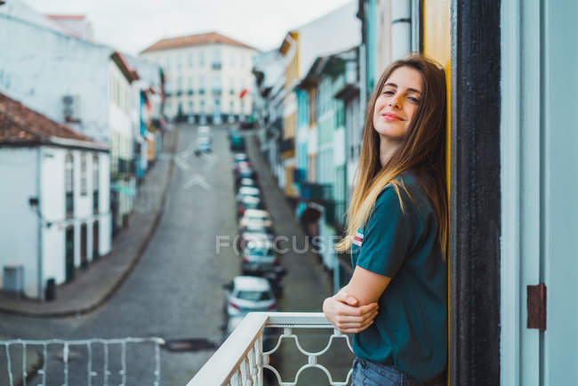 Morena alegre posando na varanda e olhando para a câmera — Fotografia de Stock