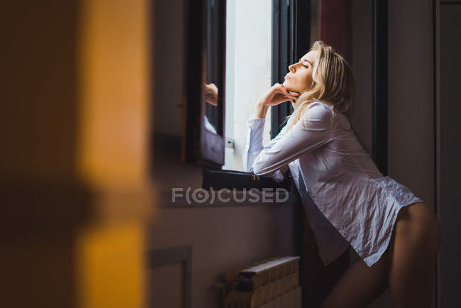Mulher atraente inclinando-se na soleira da janela — Fotografia de Stock