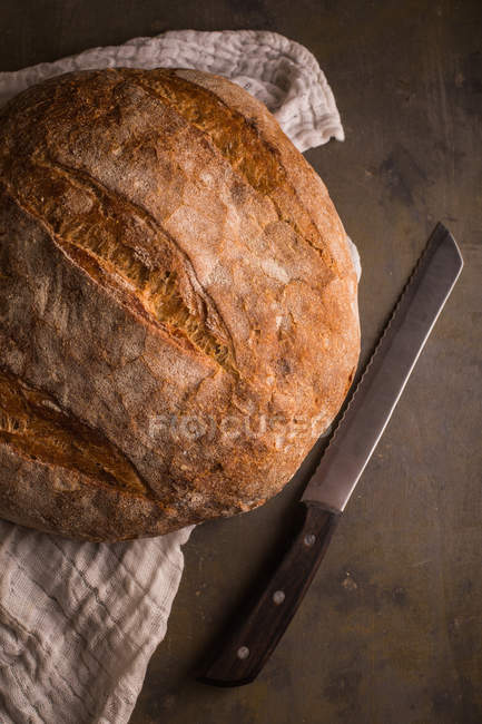 Натюрморт свежеиспеченного хлеба и ножа на темном фоне — стоковое фото