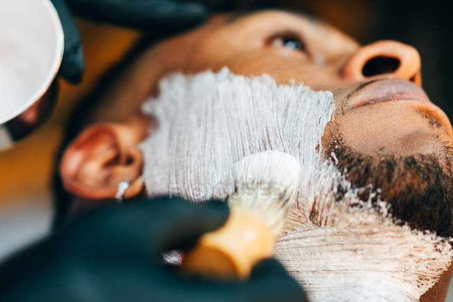 Barbier mettre de la mousse sur le visage du client — Photo de stock