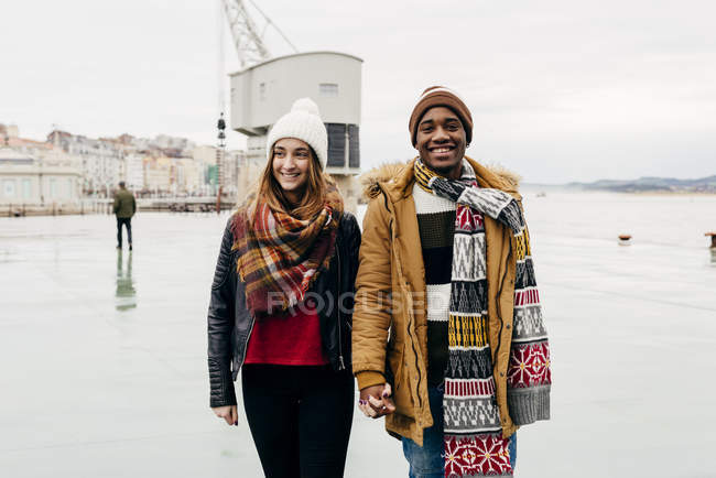 Jovem casal em pé no porto e olhando para a câmera — Fotografia de Stock
