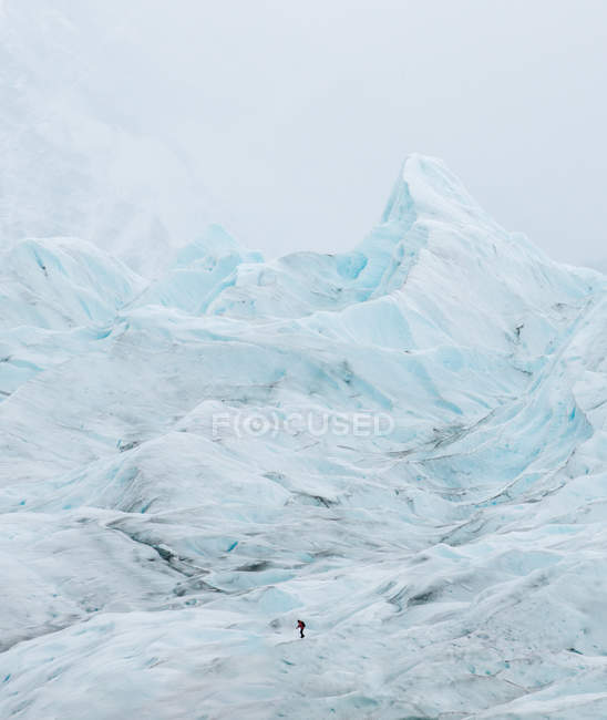 Vista lejana de un viajero irreconocible caminando sobre una montaña cubierta de nieve . - foto de stock