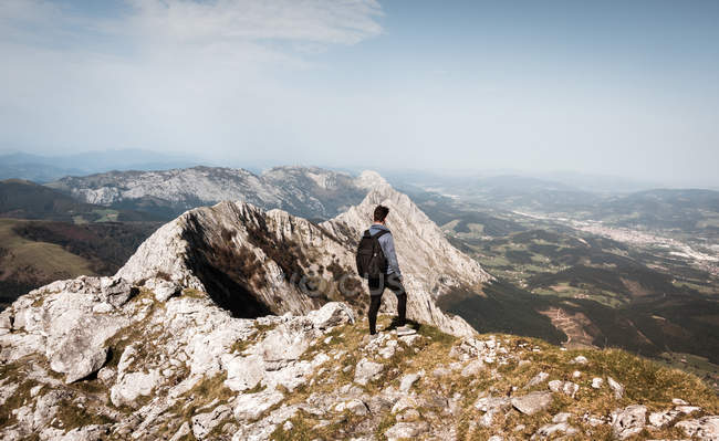 Rückansicht eines Touristenmannes mit Rucksack, der auf einem Berg steht und wegschaut. — Stockfoto