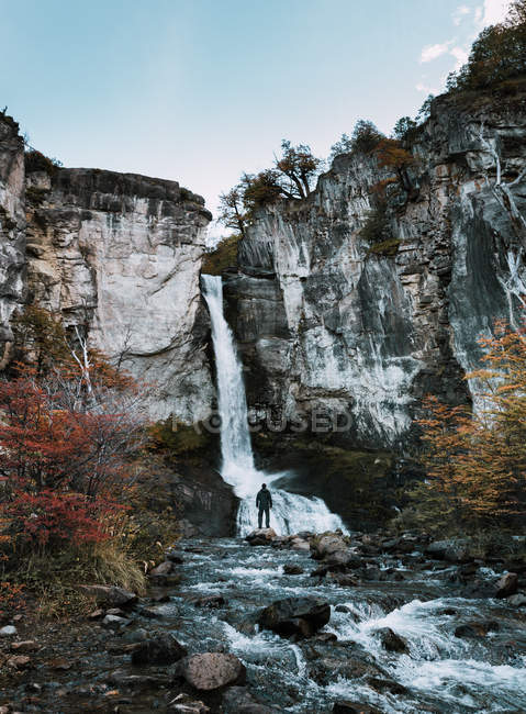 Vue arrière du randonneur debout à la cascade dans les montagnes . — Photo de stock