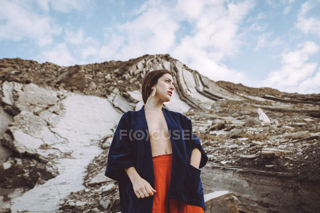 Топлес брюнетка дівчина в куртці позує над кам'янистою скелею — стокове фото