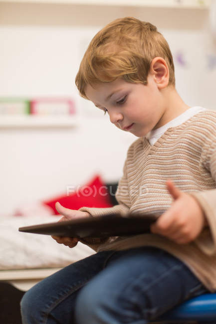 Мальчик-блондин играет с планшетом дома — стоковое фото
