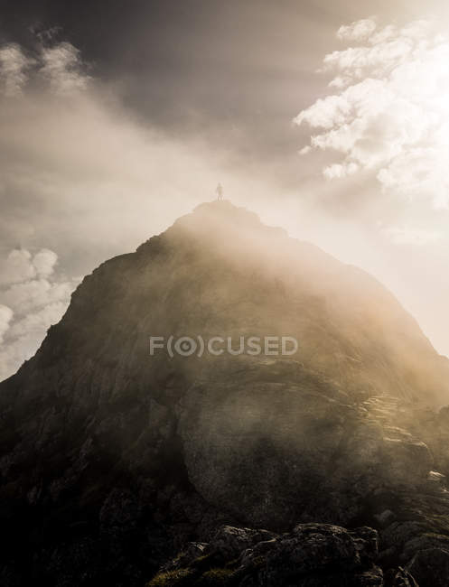 Turista irreconhecível em pé no topo da colina em luzes de pôr do sol . — Fotografia de Stock