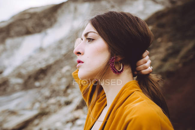 Wonderful brunette girl in yellow jacket holding hair in pony tail — Stock Photo