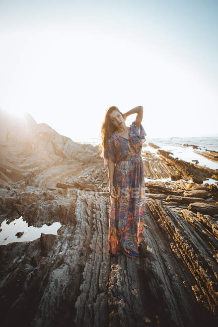 Young brunette girl posing in summer dress on rocky terrain — Stock Photo