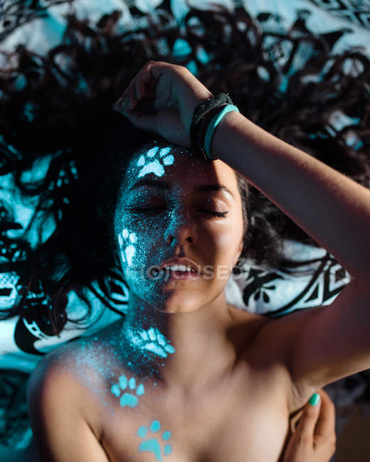Woman with fluorescent paw prints on face — Stock Photo