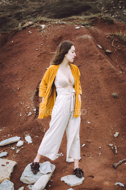 Брюнетка дівчина в бюстгальтері і жовтий піджак прокидається на узбережжі — стокове фото