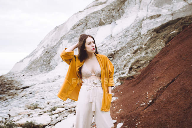 Menina morena em sutiã e casaco amarelo posando na costa — Fotografia de Stock