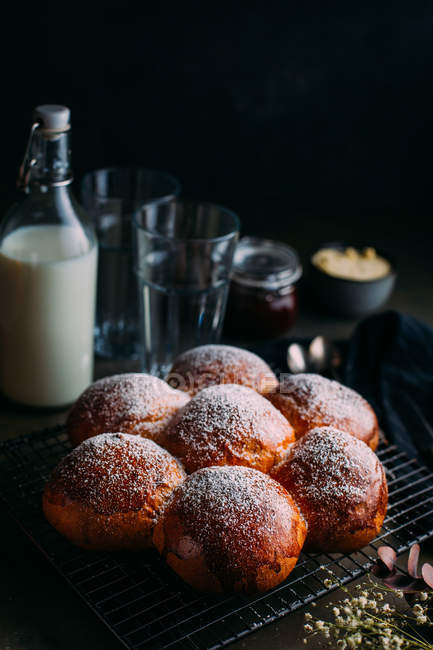 Still life of brioche with icing sugar and bottle of milk at background — Stock Photo