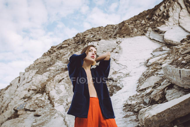 Topless brunette girl in black jacket posing at rocky cliff — Stock Photo