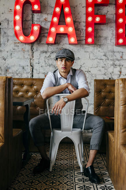 Homem de roupas vintage posando na cadeira no café — Fotografia de Stock