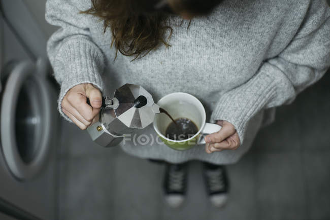 Сверху вид женщины, наливающей кофе на кухню — стоковое фото