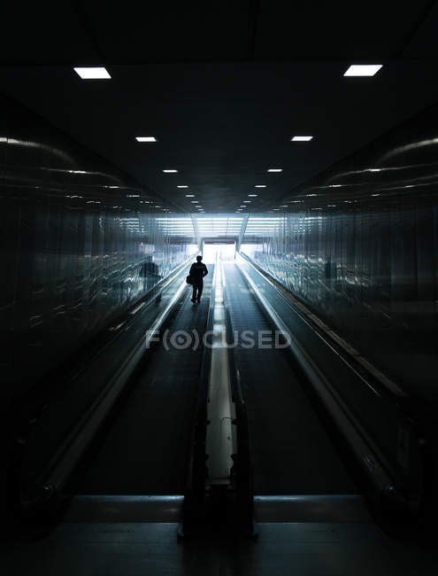 Silhouette eines nicht wiederzuerkennenden Mannes auf fahrendem Gehweg. — Stockfoto