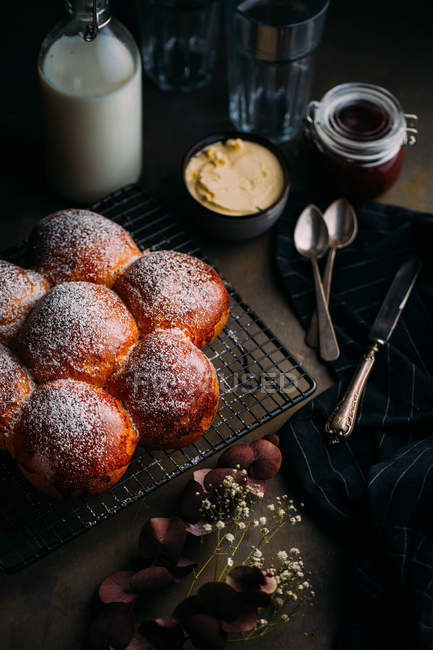 Delicious brioche with icing sugar, with bottle of milk and utensils at background — Stock Photo