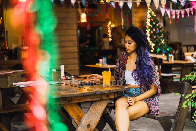 Femme avec assise à une table de café et utilisant un smartphone — Photo de stock