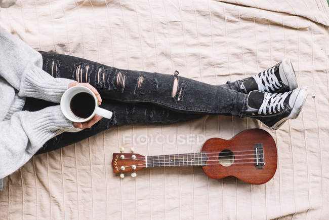 Sezione bassa di donna e ukulele sul letto — Foto stock