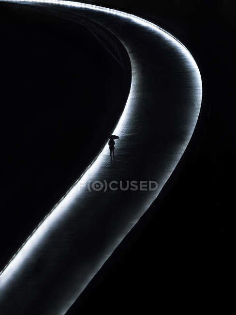 From above view of silhouette with umbrella on illuminated road at night. — Stock Photo
