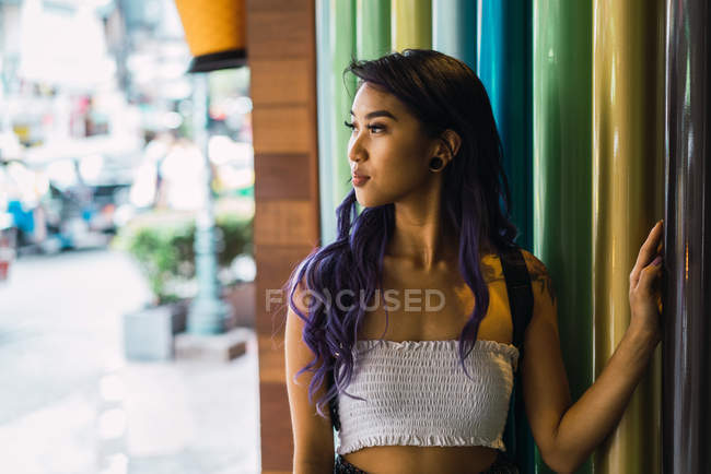 Молодая женщина опирается на красочные колонны и смотрит в сторону — стоковое фото