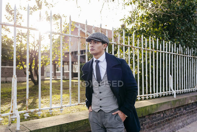 Homem de roupas vintage andando perto do portão na rua — Fotografia de Stock