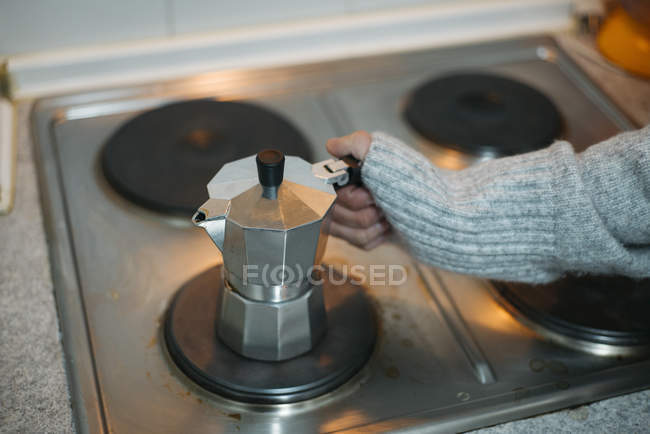 Crop hand touching coffee pot on stove — Stock Photo