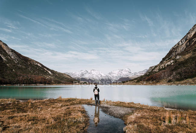 Vue arrière du randonneur avec sac à dos debout au bord du lac en montagne . — Photo de stock