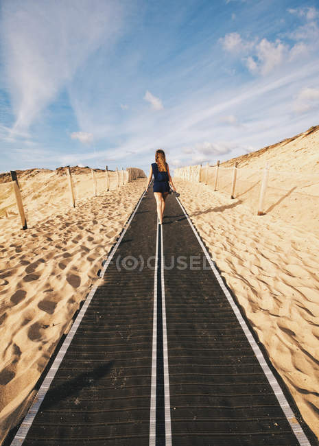 Vista posterior de la mujer bonita en la pasarela colocada en la arena . - foto de stock
