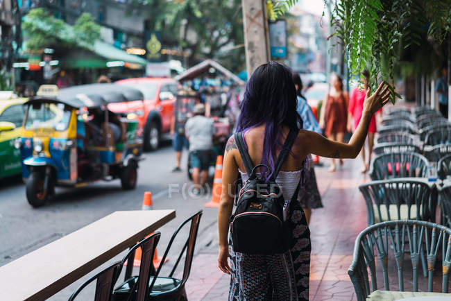 Вид ззаду жінки з фіолетовим волоссям, що йде по вулиці — стокове фото