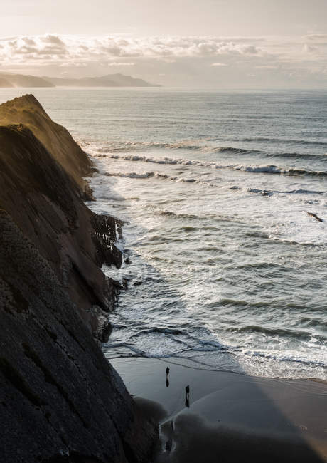 Spaziergänger am Sandstrand am Felsen am Meer. — Stockfoto