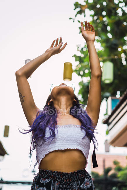 Mulher com cabelo roxo gesticulando com os braços levantados na rua — Fotografia de Stock