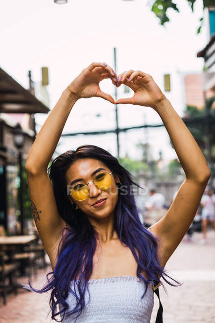 Femme aux cheveux violets gesticulant coeur dans la rue — Photo de stock