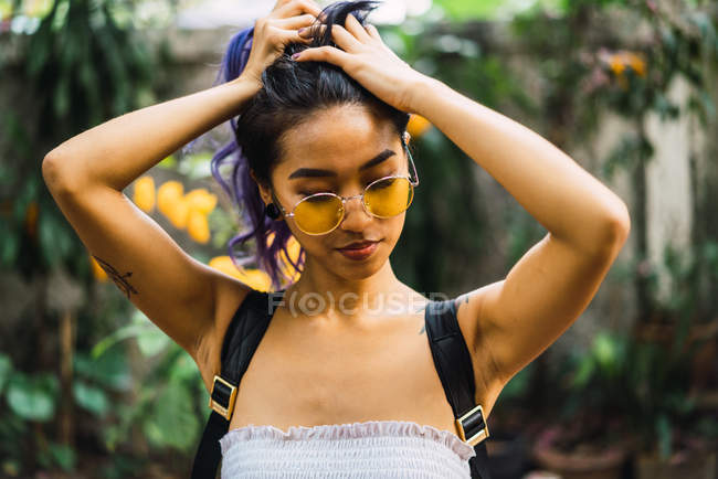 Pretty young woman holding purple hair and posing in park. — Stock Photo